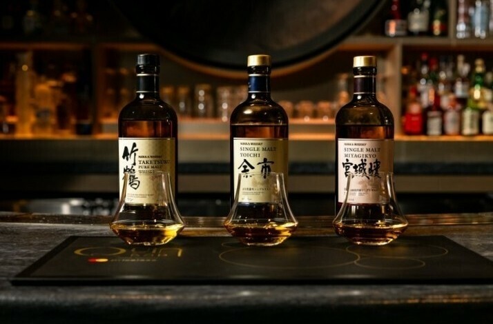 Three bottles of Nikka Japanese whiskey and tasting glasses lined up on a branded Quin Bar placemat.