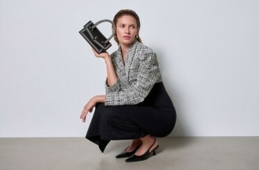 A sitting woman model, promoting Answear hand purse and clothing.