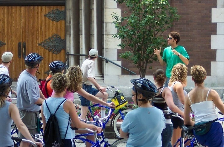 A group of tourists on bikes listening to the guide on Bobby's Bike Hike Westside Foodie Bike Tour.