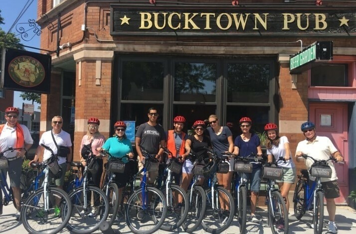 A group of tourists on bikes posing for the photo near the Bucktown Pub in Chicago