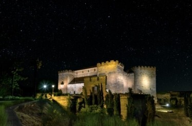 Castillo del Buen Amor illuminated at night beneath a star-filled sky in Salamanca, Spain.