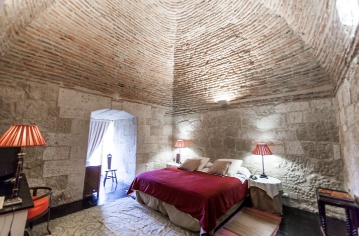 Plush double bed beneath a vaulted brick ceiling in the Tower Suite at Castillo del Buen Amor, Salamanca.