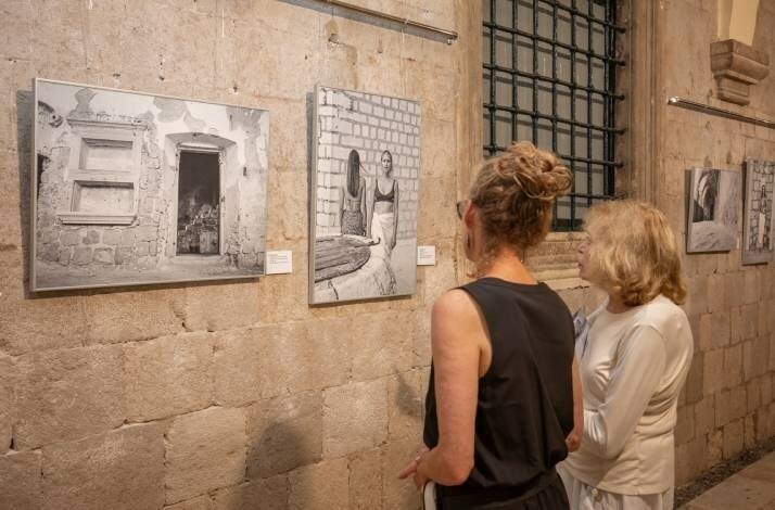 Two women viewing black-and-white photographs in an art gallery.