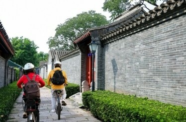 People cycling through a hutong in Beijing, China.