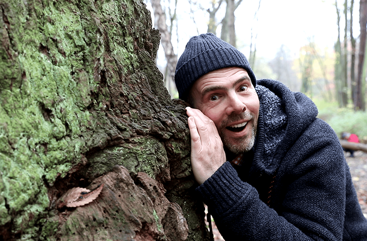 Wildlife expert Derk Ehlert peeks on a tree.
