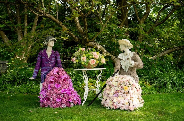 Floral arrangements in the shape of Downton Abbey characters sitting on a bench