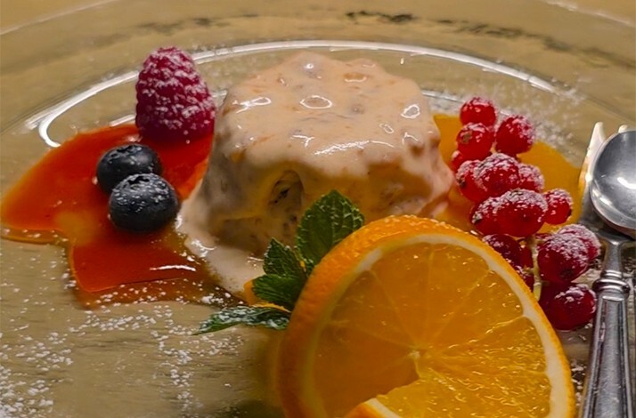 A gourmet plate dessert, probably a panna cotta or a creamy pudding with sauce