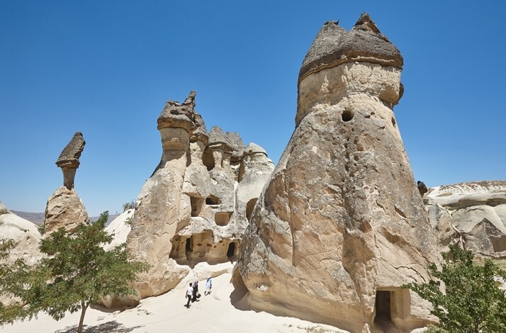 Rock formations at Paşabağ in Cappadocia, with visitors walking between the fairy chimneys.