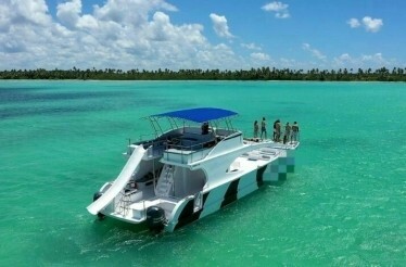 A party boat in the ocean, surrounded by clear blue waters and a bright sky.