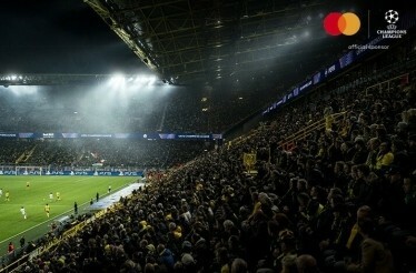 Bleachers full of football fans waving flags at an UEFA Champions League match