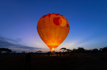 A brightly illuminated air balloon with the Priceless logo floating above the Amboseli national park.