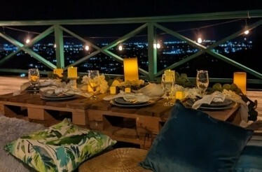 Dinning table arranged at balcony during night time with a city view.