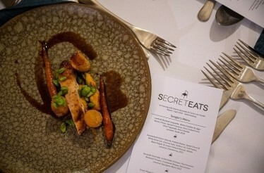 SecretEATS menu next to a dish prepared for an exclusive mystery dinner at a surprise venue in Johannesburg.