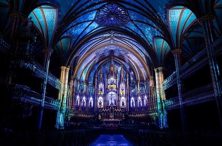 The gothic style interior lit with dim blue lights of Notre-Dame Montreal
