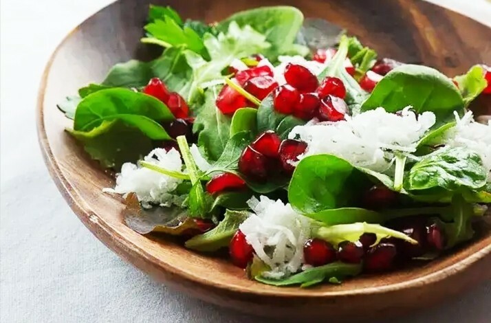 Fresh salad with pomegranate seeds and shredded white radish in a wooden bowl