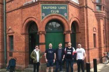 A group of tourists standing next to the entrance to Salford Lads Club in Manchester