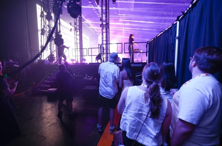 Guests viewing an artist performing at a DJ booth on stage from an exclusive side-of-stage vantage point at AO Live Presents, Melbourne Park.