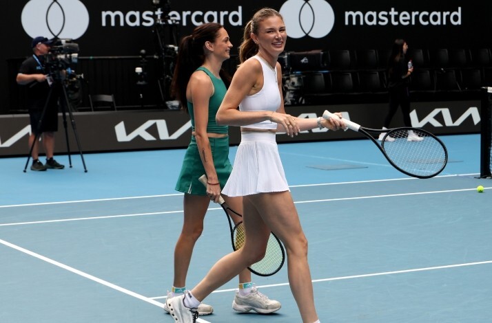 Maya Joint smiling while walking on a blue court with another player during the Australian Open.