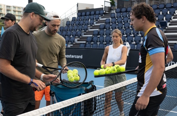 Tennis fans and coaches gathering tennis balls at a Mastercard tennis clinic during the Australian Open.