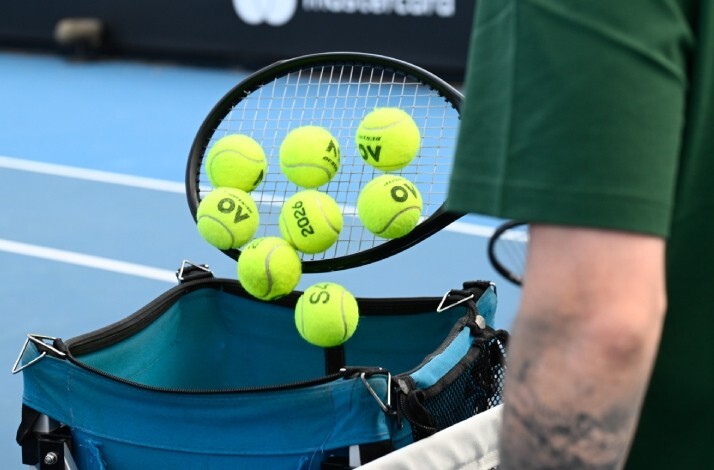 Tennis balls printed with AO and 2026 are gathered in a racket over a hopper at the Australian Open.