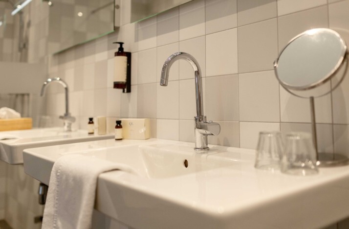 Modern hotel bathroom with white sinks, chrome faucets, toiletries, and a vanity mirror at Hotel Carelshaven.