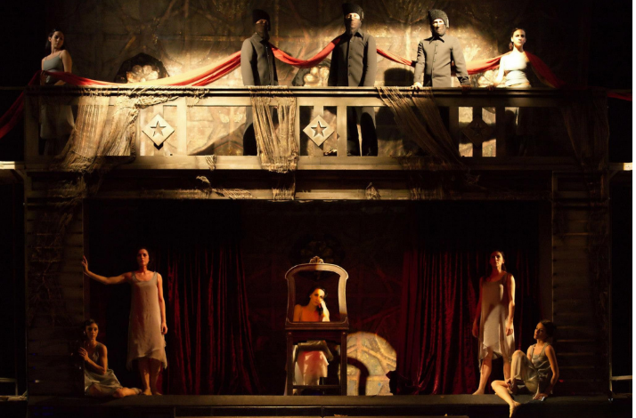 Ballet dancers performing on a theatrical stage with balcony scenery