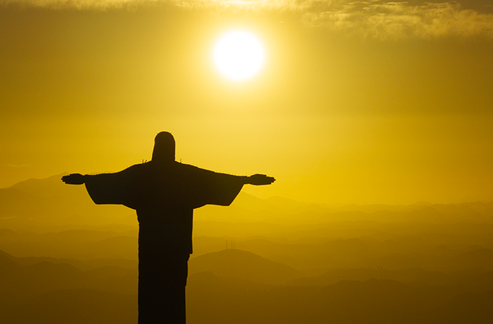 Christ the Redeemer statue silhouetted against a sunrise sky. 