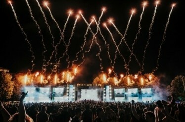 Crowd view of the stage and fireworks at an ARC Music Festival at night.