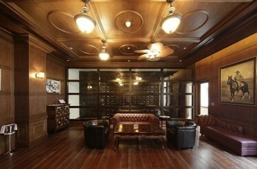 One of the halls at the House of Roosevelt with leather sofas and armchairs, wooden floor, ceiling and walls.