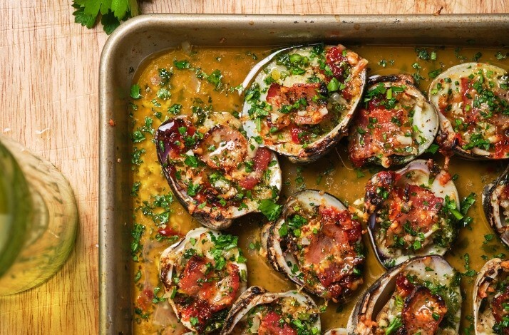  A skillet brimming with clams and aromatic herbs, showcasing a seafood dish preparation.