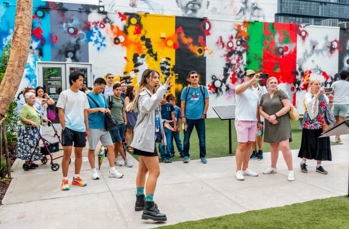 A woman guide telling people about the outdoor mural gallery and street art museum Wynwood Walls.