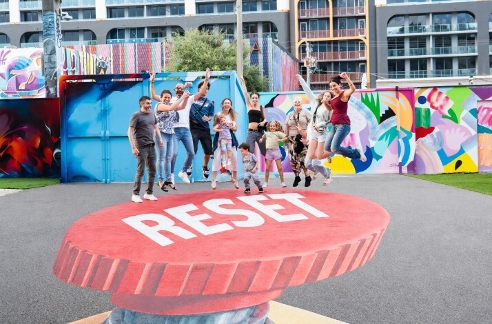 People jumping over the 'Reset' graphic art at museum Wynwood Walls.
