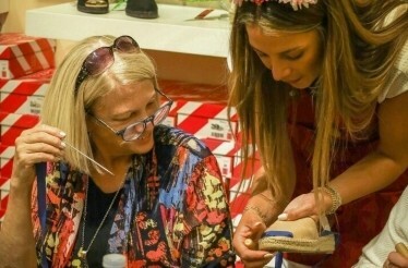 A woman assists an older woman in putting on her shoe, demonstrating care and support.