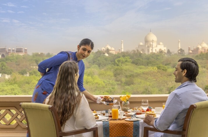 A couple enjoying their balcony lunch at the Oberoi Amarvilas, Agra with a view on Taj Mahal.