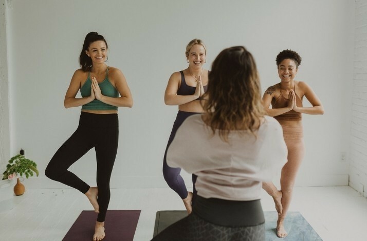 A group of people smiling doing yoga with an expert