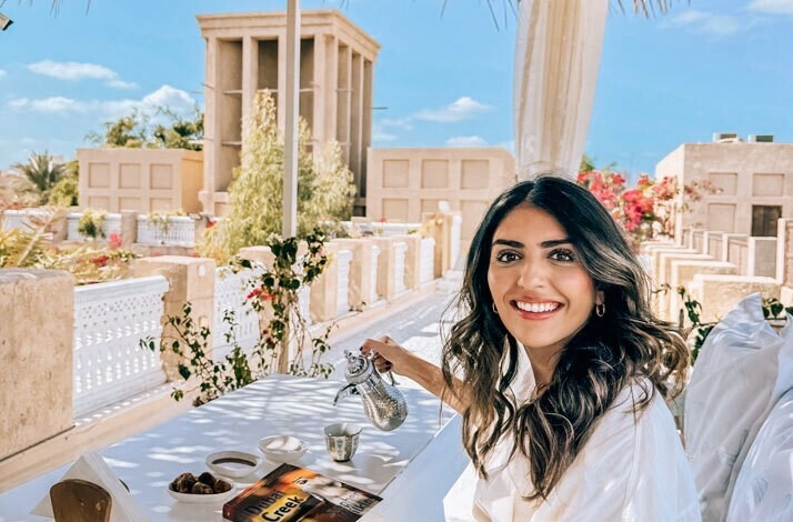A woman having an arabic beverage with a Dubai Creek book on the table