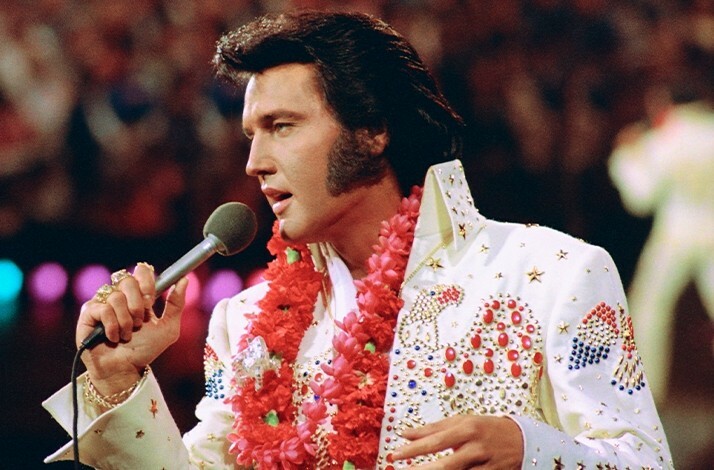 Elvis Presley in a white jacket decorated with multi-colored stones.