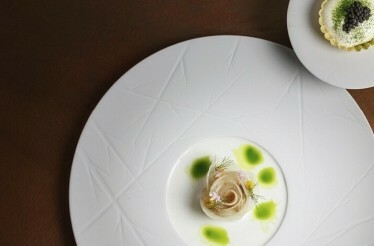 A close up shot of 2 foods on 2 separate white plates served on a red cover table at Restaurant Cèpes