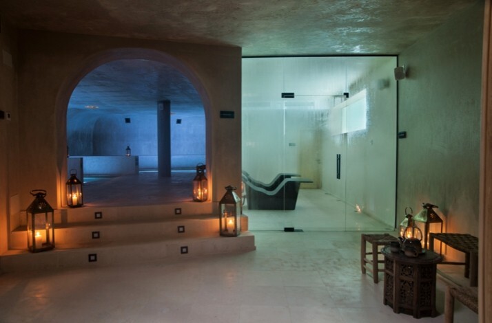 Dimly lit spa interior with arched stone walls and lanterns.
