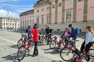Participants of Secrets of Berlin Bike Tour listening to the guide while Uncovering Berlin's secret spots in the historical place.