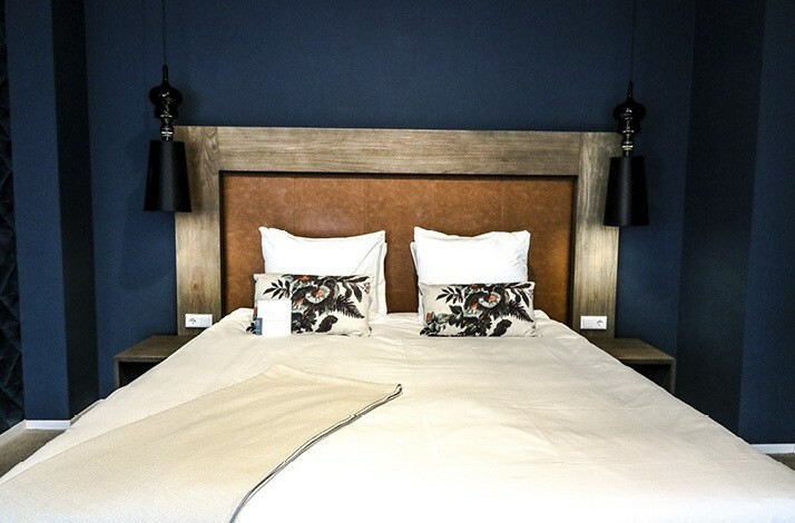 Elegant king-sized bed with plush pillows and sleek lighting in a stylish room.