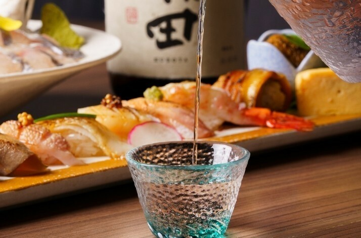 Close-up of a waiter pouring sake into a glass in ODDS & Zushi ANA