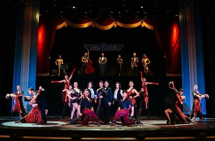 A vibrant tango performance with dancers and musicians on a grand stage