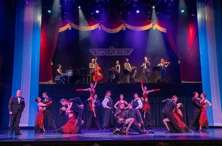A vibrant tango performance with dancers and musicians on a grand stage