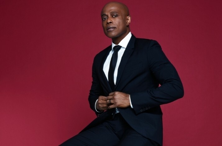 Promotional photo of Grammy-nominated singer and multi-platinum recording artist Kem on a burgundy background.