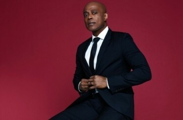 Promotional photo of Grammy-nominated singer and multi-platinum recording artist Kem on a burgundy background.