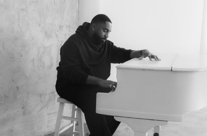 Black and white banner of DIXSON sitting at a white piano, representing premium seating for his live Blue Note LA show.