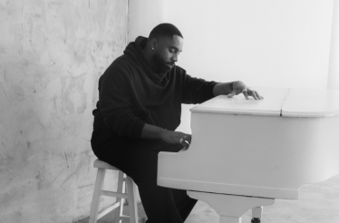 Black and white banner of DIXSON sitting at a white piano, representing premium seating for his live Blue Note LA show.