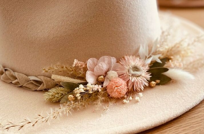 A beige hat adorned with delicate pastel flowers and braided trim