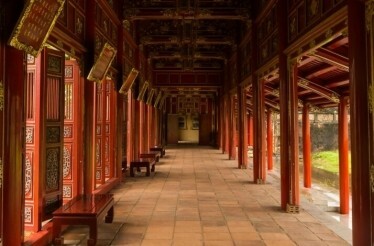 A long, red-columned hallway within the Hue Imperial City, which extends into the distance, showcasing ornate architecture.